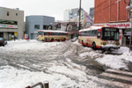 雪の日の福生駅西口広場のようすです。西東京バスの車体にも雪が積もっています。福生駅は日出町方面への玄関口として西口には多くのバスがやってきます。